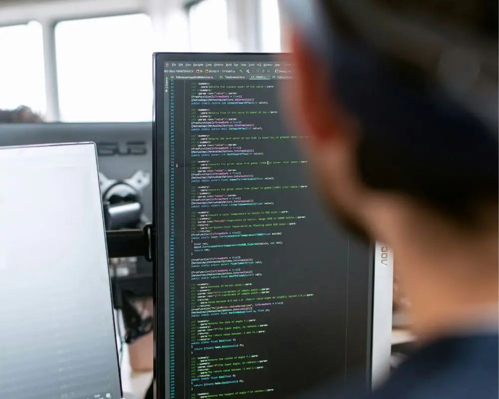 IT specialist reviewing software code on a computer monitor