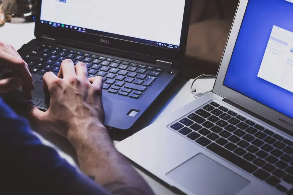IT professional working on two laptops for technical support